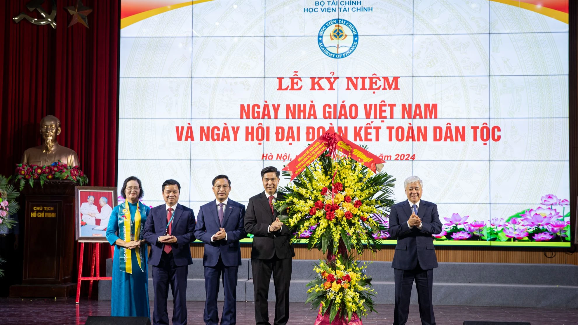 Đồng chí Đỗ Văn Chiến tặng hoa, chúc mừng các thầy giáo, cô giáo và toàn thể sinh viên Học viện Tài chính. (Ảnh: SƠN TÙNG)
