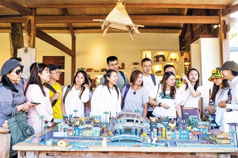 Du khách tìm hiểu nghệ thuật điêu khắc gỗ tại Làng Củi Lũ.