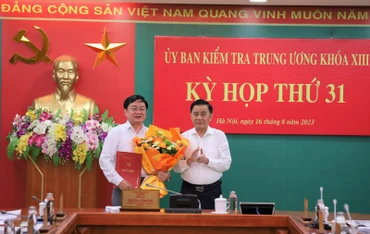 Đồng chí Trần Cẩm Tú, Ủy viên Bộ Chính trị, Bí thư Trung ương Đảng, Chủ nhiệm Ủy ban kiểm tra Trung ương trao quyết định và tặng hoa chúc mừng đồng chí Nguyễn Văn Quyết.