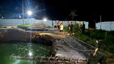Lực lượng chức năng và người dân tìm kiếm tại khu vực hố sụt trong đêm 26/7. (Ảnh: TUẤN SƠN).