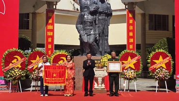 Đồng chí Dương Văn Trang trao tặng cờ và danh hiệu Anh hùng Lực lượng vũ trang nhân dân cho đại diện Tập thể chiến sĩ cách mạng bị địch bắt tù đày tại Ngục Kon Tum. 