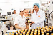 Kỹ sư Lê Ðức Anh (ngoài cùng, bên phải) kiểm tra thành phẩm tại dây chuyền đóng nước tương của Công ty cổ phần Thực phẩm Cholimex.