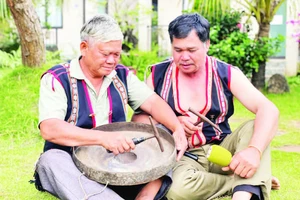 Nghệ nhân Ưu tú Đinh Dôch (bên trái) hướng dẫn kỹ thuật chỉnh chiêng cho học viên. (Ảnh LAM NGUYÊN)