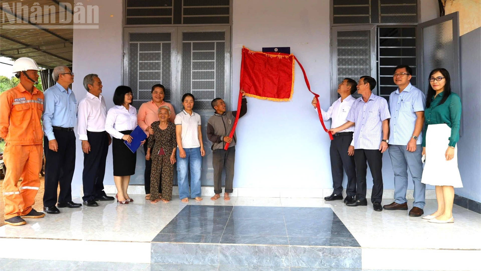 Các đại biểu và gia đình anh Nguyễn Hữu Dũng thực hiện nghi thức kéo băng khánh thành ngôi nhà.