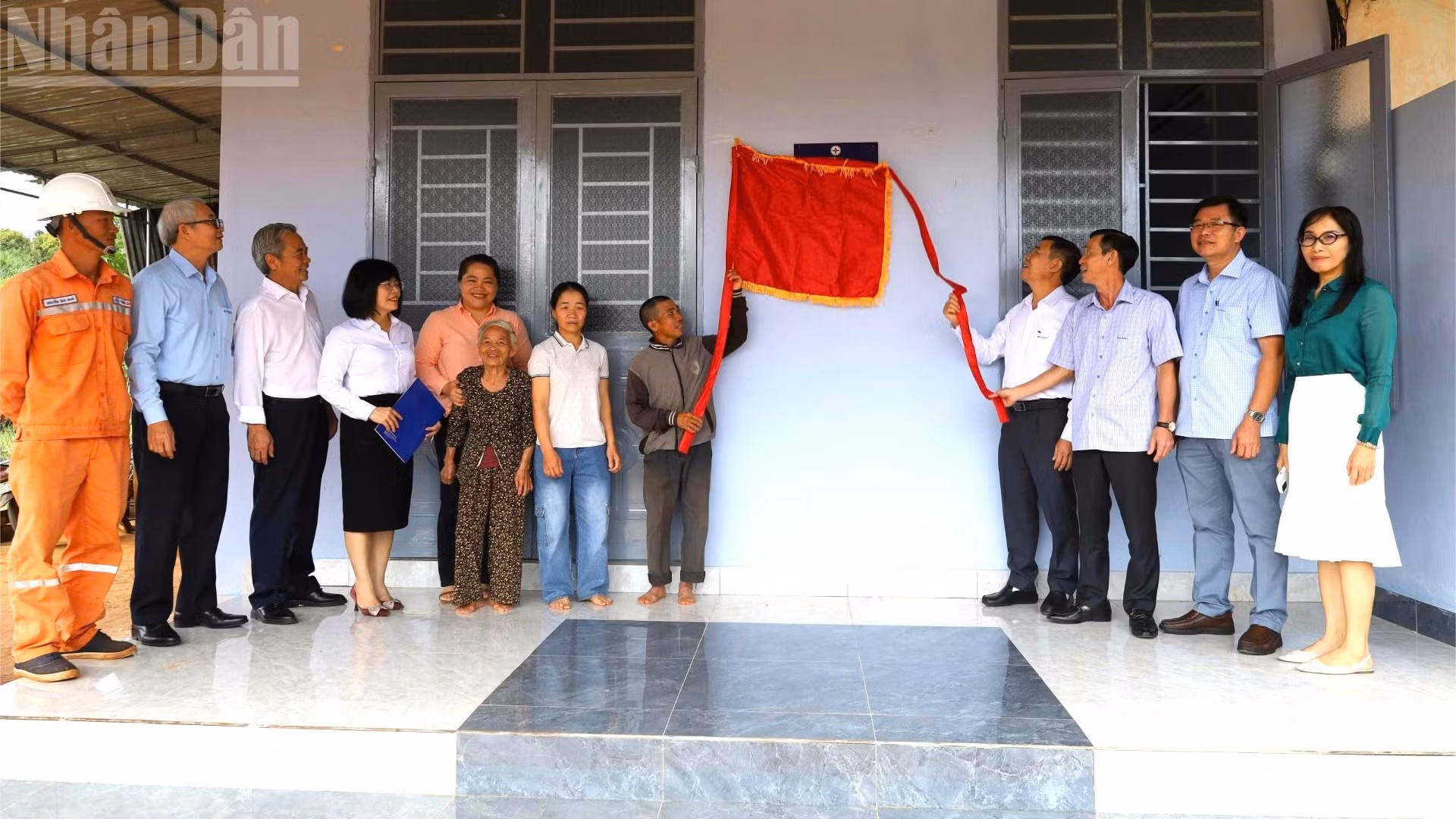 Các đại biểu và gia đình anh Nguyễn Hữu Dũng thực hiện nghi thức kéo băng khánh thành ngôi nhà.