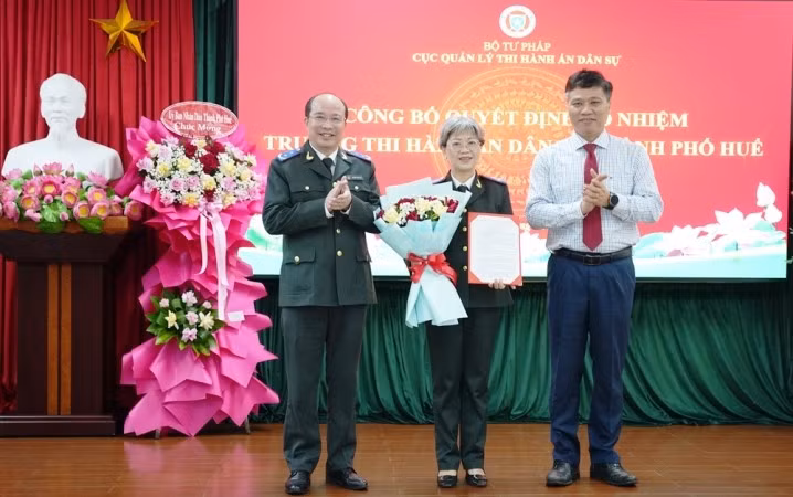 Cục trưởng Cục Quản lý Thi hành án dân sự Nguyễn Thắng Lợi và Trưởng Ban Tổ chức Thành ủy Huế Phan Xuân Toàn trao quyết định, tặng hoa chúc mừng bà Phan Thùy Dương.