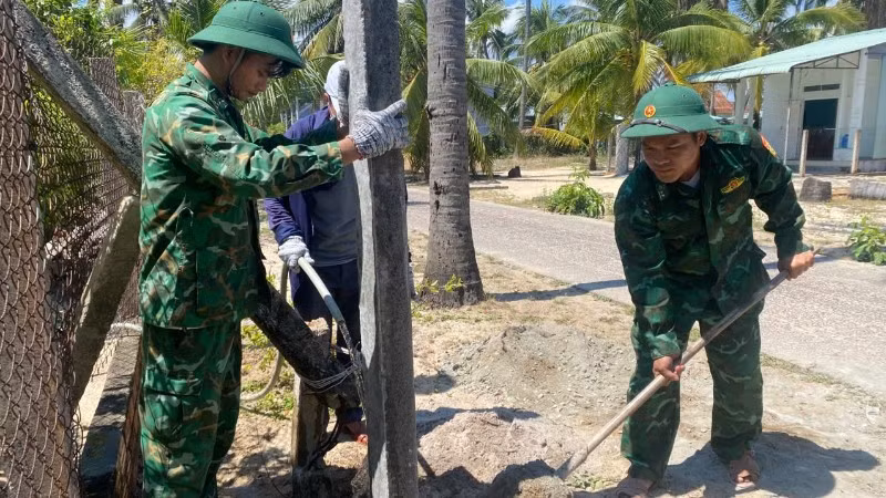 Cán bộ, chiến sĩ Đồn Biên phòng Xuân Hòa phối hợp lực lượng địa phương tham gia dựng cột điện, hoàn thiện các hạng mục của mô hình “Thắp sáng đường quê” tại Thôn 4, xã Xuân Lộc.