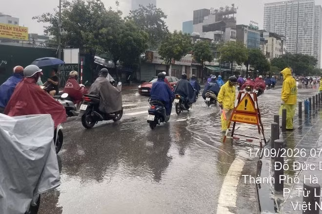 Công nhân thoát nước ứng trực, khơi thông thoát nước sáng 17/9 tại điểm ngập nước trên phố Đỗ Đức Dục, hướng dẫn giao thông cho người dân. (Ảnh: THU THỦY)