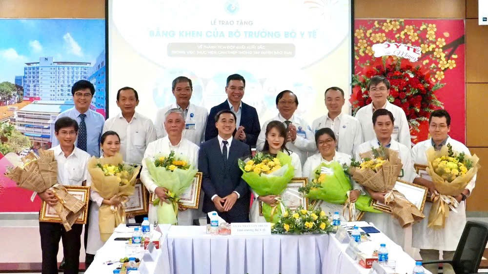 Thứ trưởng Y tế Trần Văn Thuấn tặng hoa và bằng khen cho ekip thực hiện ca can thiệp bào thai cho sản phụ người Singapore. (Ảnh: HOÀNG HÙNG)