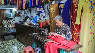 Bà Lê Thị Quyến, chủ hiệu áo dài Vinh Trạch ở phố Lương Văn Can, quận Hoàn Kiếm (Hà Nội) dù tuổi cao nhưng vẫn miệt mài bên bàn máy để trực tiếp làm ra những sản phẩm áo dài mang đúng thương hiệu Trạc