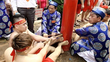 Hai đội kéo dưới sự phân định của trọng tài, cùng đạp chân vào cột để tạo lực.