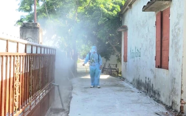 Nhân viên y tế phun hóa chất tiêu độc, khử trùng cụm dân cư trong bán kính 200, nơi có người nghi nhiễm Covid-19.