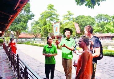 Tình nguyện viên du lịch hướng dẫn cho du khách nước ngoài về di tích lịch sử Văn Miếu - Quốc Tử Giám.Ảnh: MINH HÀ