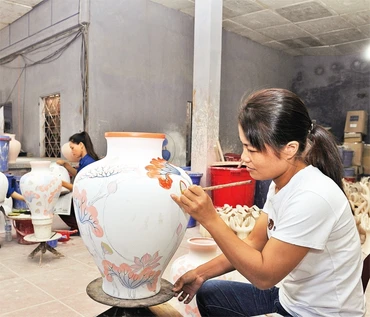 Vẽ hoa văn lên sản phẩm gốm Bát Tràng. Ảnh: HÀ THU