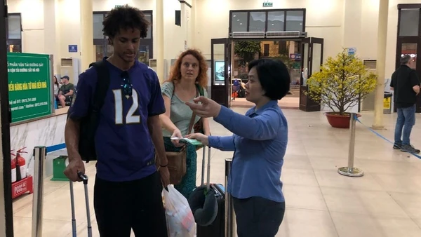 Nhân viên khách vận hướng dẫn hành khách vào ga đi tàu.