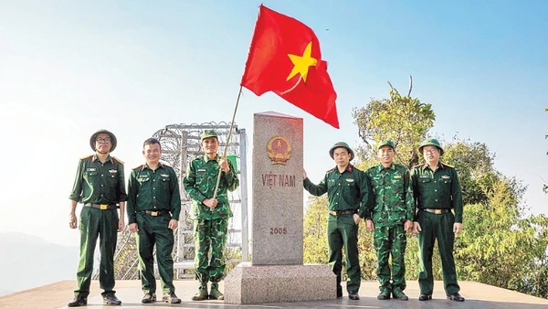 Thượng úy Lục Vĩnh Lương (người cầm cờ) cùng tác giả và đoàn công tác tại Cột mốc số 0 - Ngã ba biên giới A Pa Chải - Cực tây Tổ quốc.