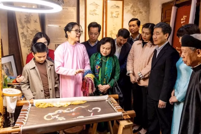 Du khách tìm hiểu nghề thêu tại đình Tú Thị, một điểm đến di sản trong tuyến đình thờ Tổ nghề.