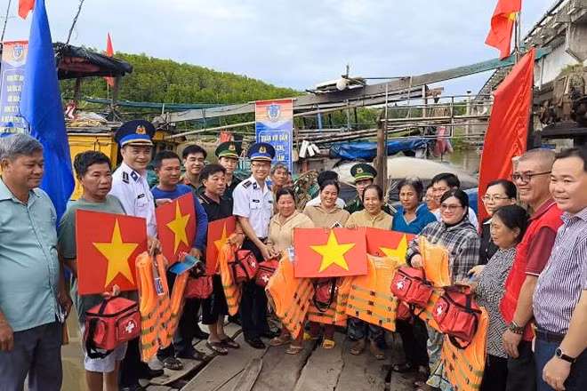 Đại diện Bộ Tư lệnh Vùng Cảnh sát biển 3 và Ban Tuyên giáo và Dân vận Tỉnh ủy Vĩnh Long tặng cờ Tổ quốc, áo phao, túi thuốc y tế... cho ngư dân.