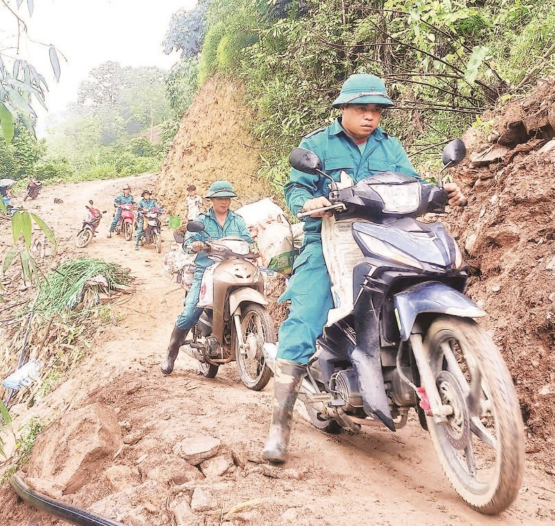Lực lượng dân quân dùng xe máy chở gạch lên núi giúp xây nhà mới cho người dân thôn Phia Bay.