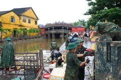 Các cán bộ, chiến sĩ Trường Quân sự Quân khu 5 thu dọn và vận chuyển lượng lớn rác tích tụ tại khu vực chùa Cầu Hội An sau lũ.