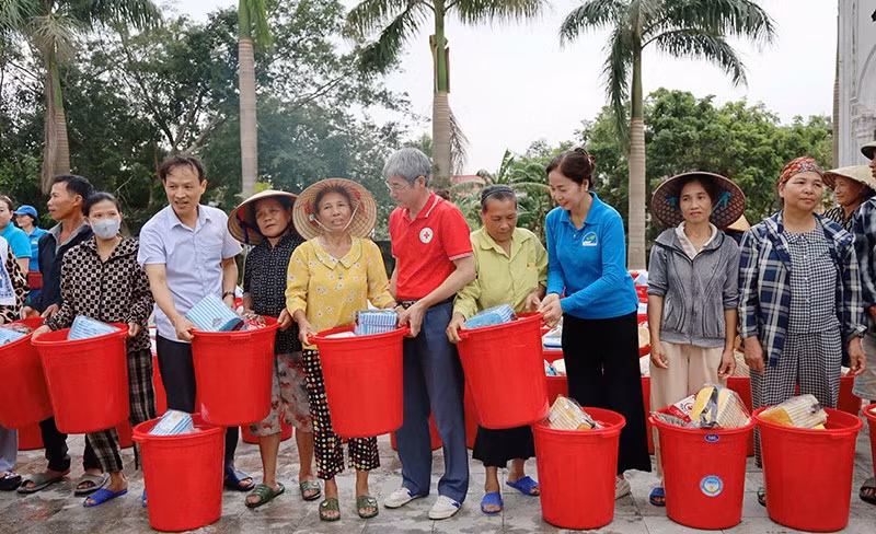 Lãnh đạo cùng các tình nguyện viên Chữ thập đỏ trao hàng thiết yếu tới nhân dân vùng thiệt hại do thiên tai ở Thanh Hóa.