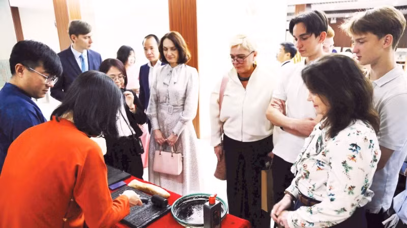 Du khách nước ngoài thích thú khi trải nghiệm in dập mộc bản.