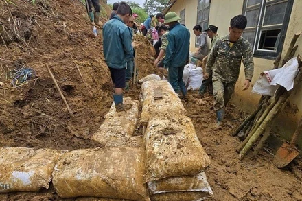 Cán bộ, chiến sĩ Ban Chỉ huy Bộ đội Biên phòng tỉnh Điện Biên cùng người dân dọn nhà cửa, khắc phục hậu quả do lũ quét. (Ảnh: LÊ LAN)