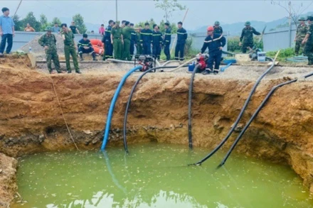 Lực lượng chức năng bơm hút nước tìm kiếm nạn nhân. (Ảnh: TUẤN SƠN)