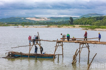 Người dân xây dựng lại cầu gỗ Ông Cọp sau khi công trình bị lũ cuốn đi vào tháng 11 vừa qua.