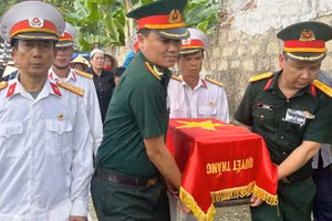 Lực lượng vũ trang cùng các cựu chiến binh di chuyển hài cốt liệt sĩ.