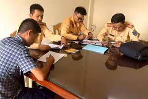 Cảnh sát giao thông lập biên bản về hành vi vi phạm của người điều khiển ô-tô.