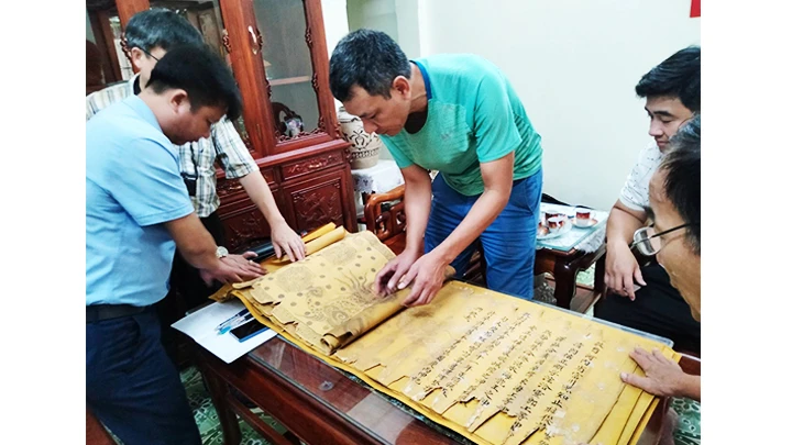 Nhà sưu tập Đặng Vũ Khương cùng đại diện người dân Tri Chỉ kiểm tra tình trạng sắc phong. Ảnh: NCVV