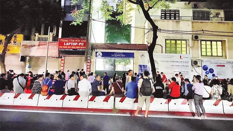 Phụ huynh học sinh xếp hàng chờ mua hồ sơ cho con nhập học vào trường Trung học phổ thông Tạ Quang Bửu, Hà Nội. (Ảnh: Trang Linh)