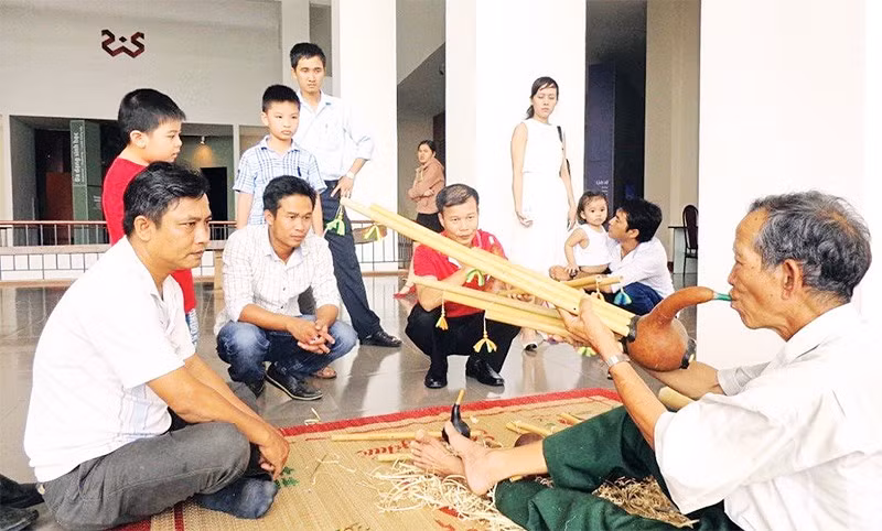 Nghệ nhân Ama Hloan ở buôn Akô Dhông, phường Buôn Ma Thuột, tỉnh Đắk Lắk giới thiệu nhạc cụ Đinh Năm với du khách.