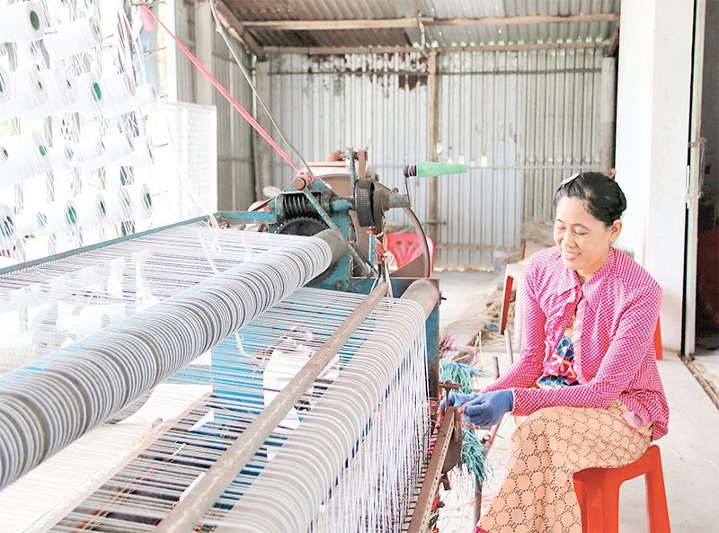 Bà Nguyễn Thị Minh Trang, chủ cơ sở dệt chiếu ấp Ðức Mỹ, xã Nhị Long, tỉnh Vĩnh Long dệt chiếu bằng máy bán tự động.