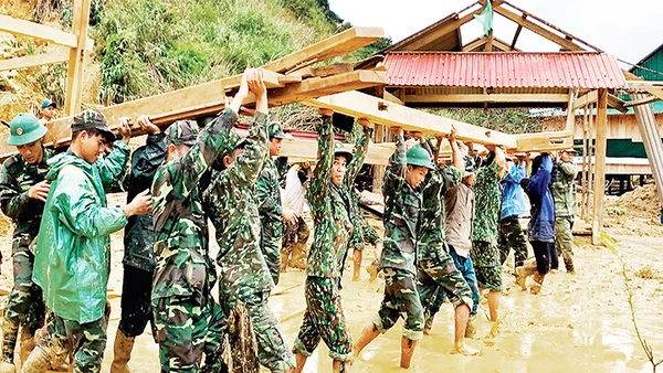 Cán bộ, chiến sĩ Đồn Biên phòng Ga Ry (Bộ Chỉ huy Bộ đội Biên phòng tỉnh Quảng Nam) giúp nhân dân huyện Tây Giang dựng lại nhà sau bão. Ảnh: PHAN TIẾN DŨNG