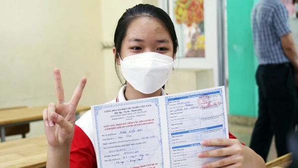 Trẻ được tiêm và nhận chứng nhận tiêm vắc-xin phòng Covid-19.