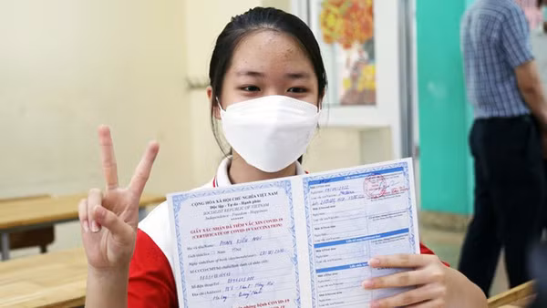 Trẻ được tiêm và nhận chứng nhận tiêm vắc-xin phòng Covid-19.