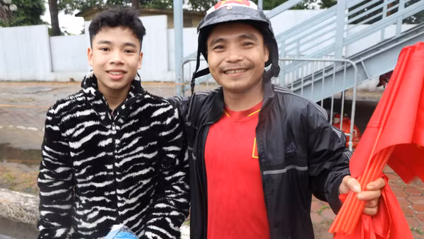 Hai cha con anh Nam bán cờ với hy vọng có thêm tiền để mua vé vào sân. (ẢNH: Sơn Bách)