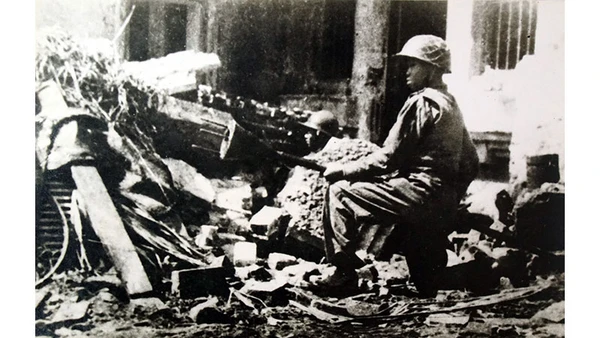 Chiến sĩ Trần Thành, đoàn viên Thanh niên cứu quốc Hoàng Diệu, ôm bom ba càng, sẵn sàng tiêu diệt xe tăng địch trên đường phố Thủ đô Hà Nội ngày 23-12-1946 - những ngày đầu Toàn quốc kháng chiến, với ý chí "Quyết tử cho Tổ quốc quyết sinh". Ảnh: Nguyễn Bá Khoản (TTXVN)