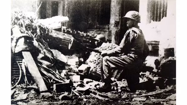 Chiến sĩ Trần Thành, đoàn viên Thanh niên cứu quốc Hoàng Diệu, ôm bom ba càng, sẵn sàng tiêu diệt xe tăng địch trên đường phố Thủ đô Hà Nội ngày 23-12-1946 - những ngày đầu Toàn quốc kháng chiến, với ý chí "Quyết tử cho Tổ quốc quyết sinh". Ảnh: Nguyễn Bá Khoản (TTXVN)