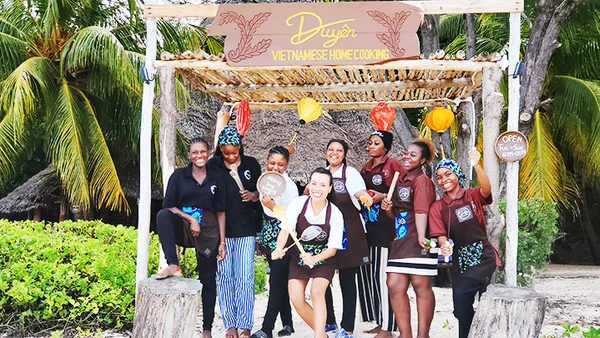 Kim Anh (hàng đầu) cùng nhân viên địa phương trước cổng nhà hàng.