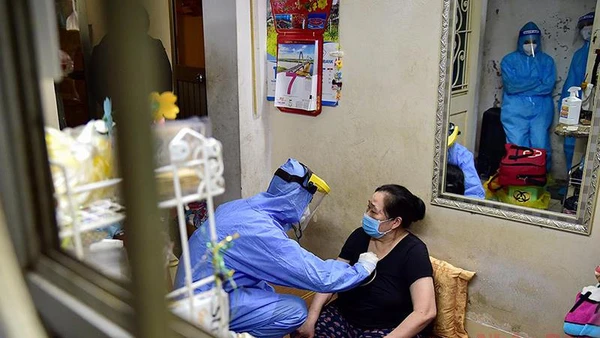 Nhân viên y tế khám sàng lọc trước khi tiêm chủng cho người dân tại nhà. (Ảnh: THÀNH ĐẠT)