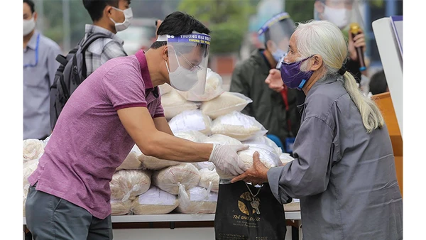 Tình nguyện viên phát gạo cho người nghèo bị ảnh hưởng do dịch Covid-19 tại quận Hai Bà Trưng (Hà Nội). Ảnh: CTV