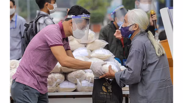 Tình nguyện viên phát gạo cho người nghèo bị ảnh hưởng do dịch Covid-19 tại quận Hai Bà Trưng (Hà Nội). Ảnh: CTV