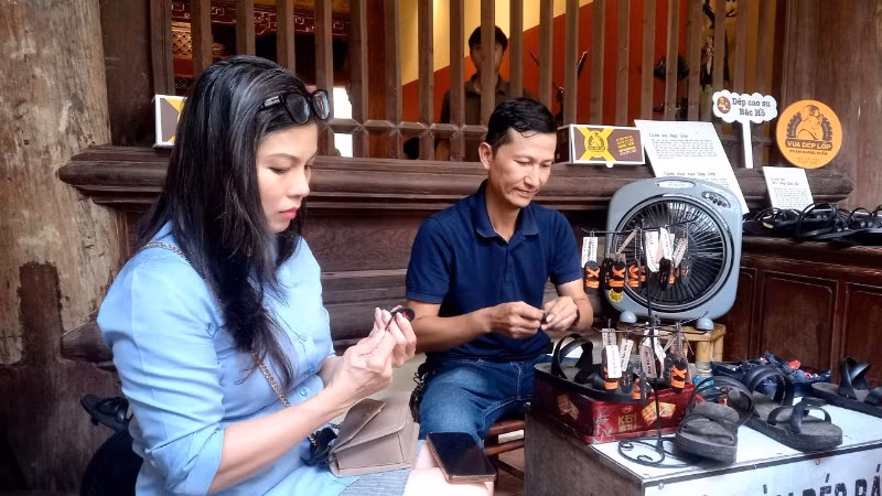 Khách tham quan tìm hiểu cách làm những chiếc dép cao-su mi-ni được dùng làm móc chìa khóa, quà tặng.