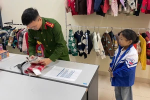 Gấp áo ấm tặng trẻ nhỏ đến làm thẻ căn cước. (Ảnh: HƯƠNG LAN).