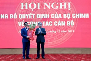 Đồng chí Nguyễn Quang Dương, Phó Trưởng ban Tổ chức Trung ương (bên phải) trao quyết định và tặng hoa chúc mừng đồng chí Vương Quốc Tuấn. (Ảnh: TUẤN SƠN)