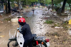 Người dân quay đầu xe trước con đường ngập rác thải sau lụt.