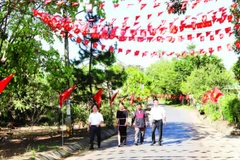 Các tuyến đường dẫn vào buôn Tuôr, xã Hòa Phú rợp đỏ màu cờ Tổ quốc chào mừng Đại hội XIV của Đảng.